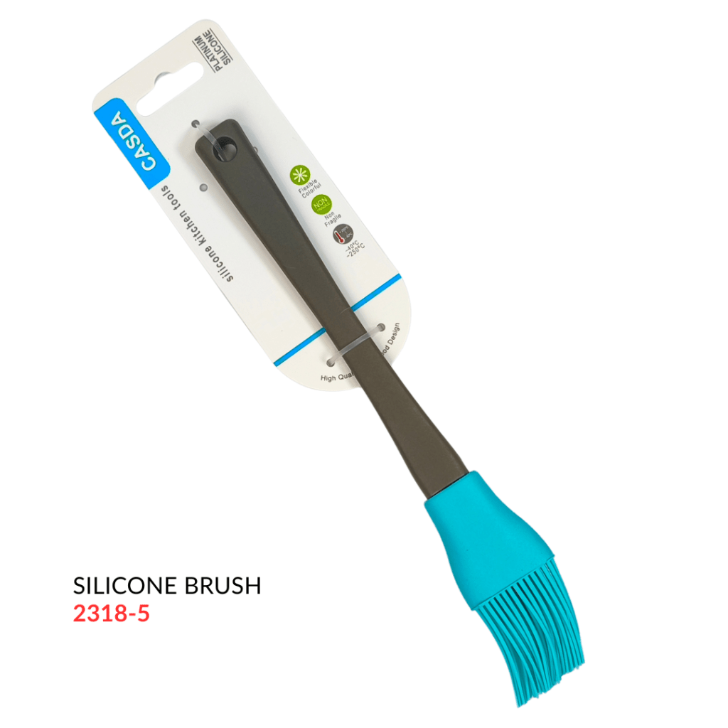 A silicone brush with a turquoise handle and a flexible bristle head, displayed with packaging showing product details.