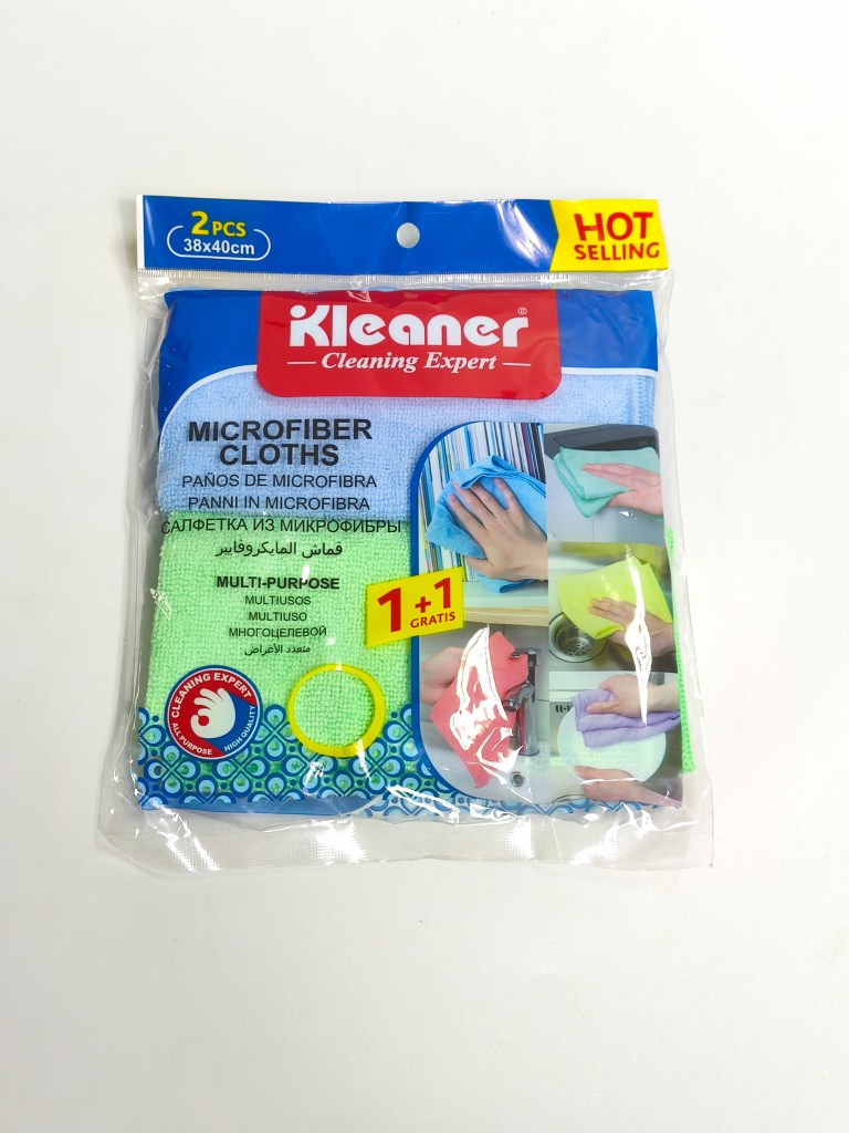 Pack of two microfiber cleaning cloths in a resealable bag, featuring a blue and green cloth, labeled 'Kleaner Cleaning Expert' with a 'Hot Selling' tag. Includes information in multiple languages and a promotion for '1 + 1 Gratis'.